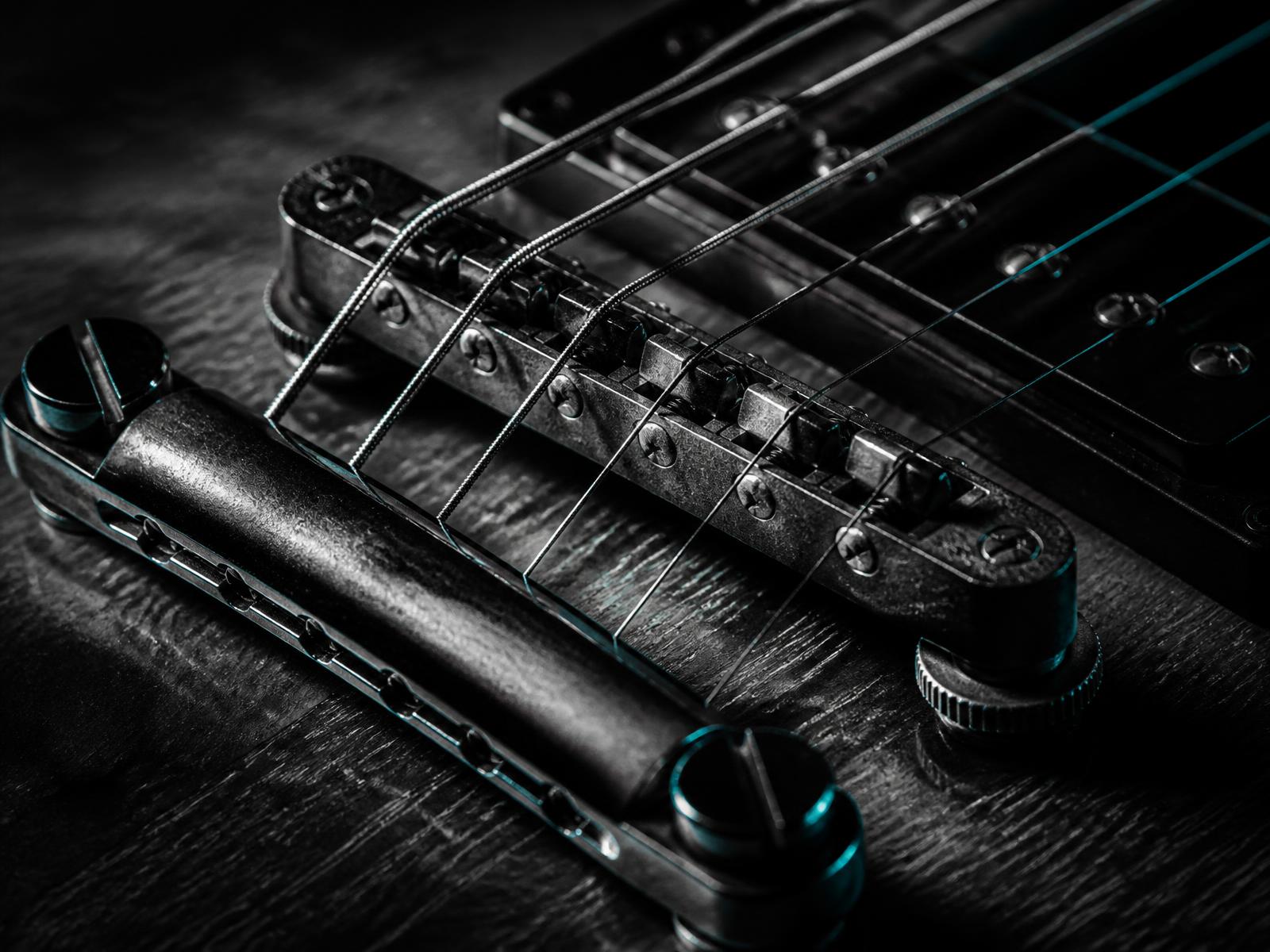 Close-up of an electric guitar bridge and strings in high-contrast monochrome